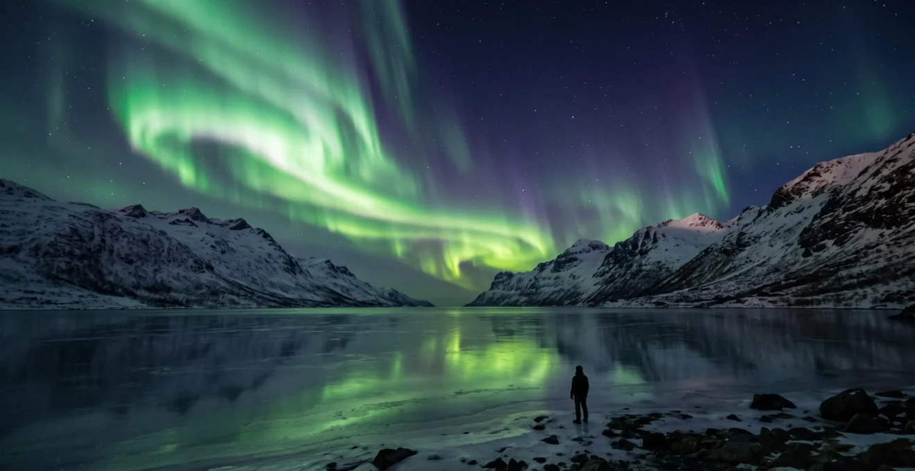 Aurore boréale verte et violette dansant au-dessus d'un paysage arctique enneigé avec un lac gelé au premier plan
