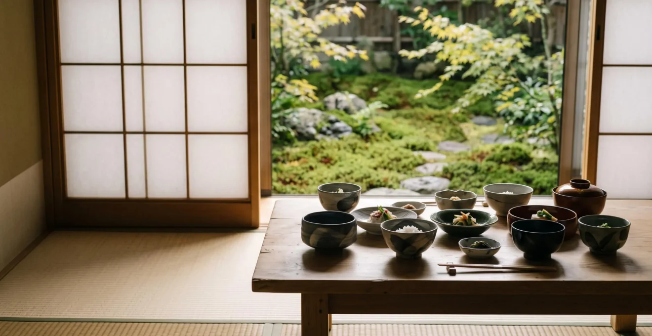 Table basse dans un ryokan japonais dressée pour un repas kaiseki avec vaisselle en céramique artisanale et jardin visible en arrière-plan